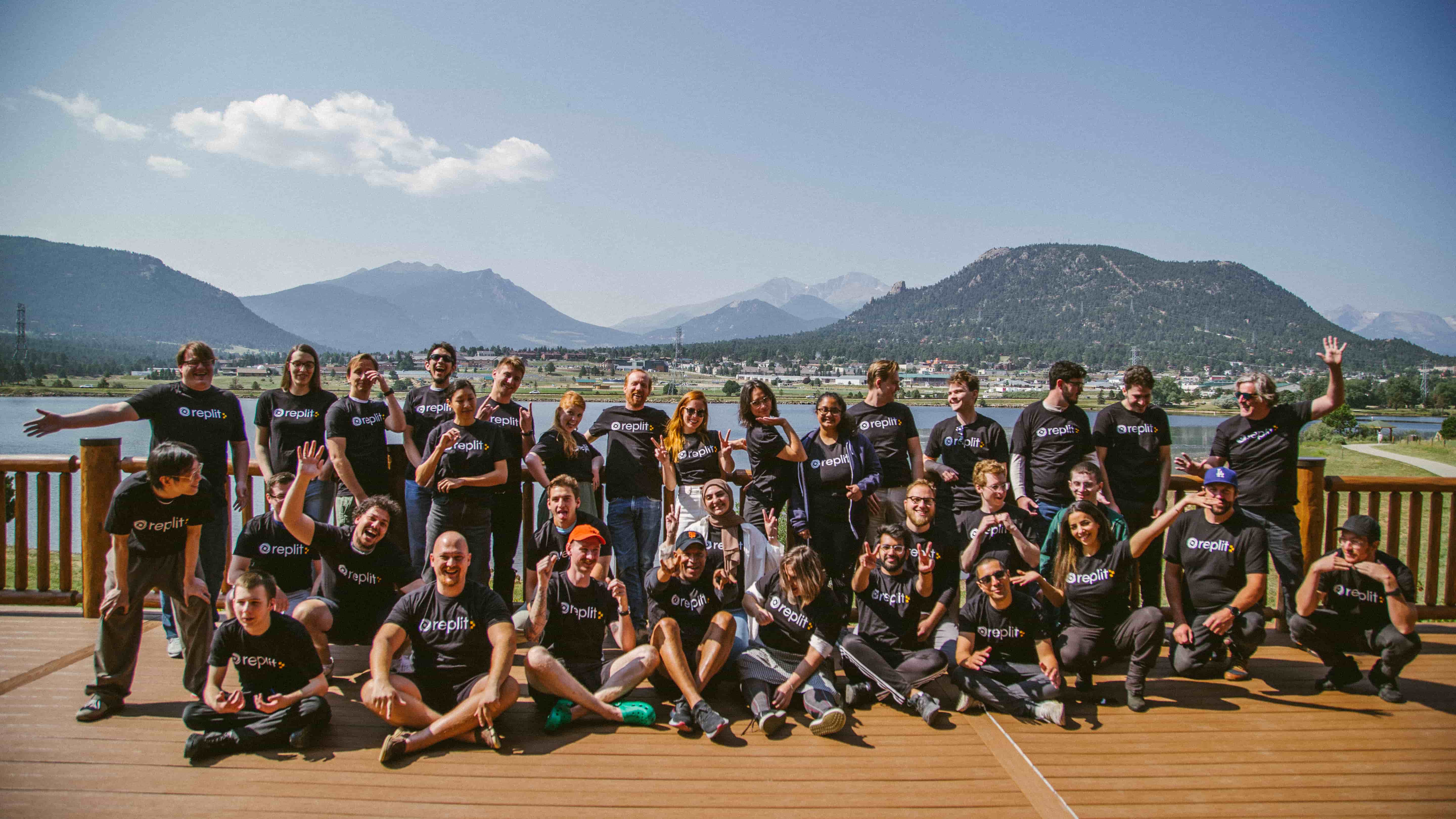 the entire Replit team together wearing company t-shirts in front of a lake in the mountains